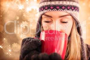 Composite image of happy blonde in winter clothes holding mug