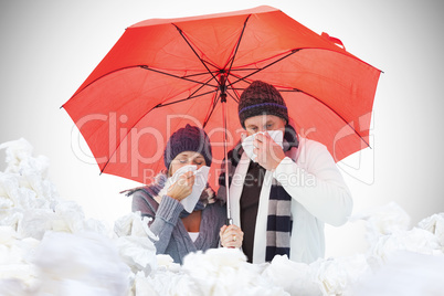 Composite image of mature couple blowing their noses under umbre