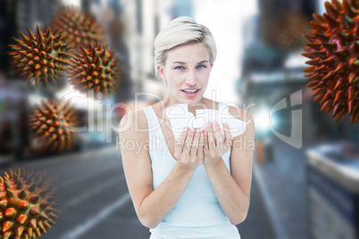 Composite image of sick woman holding tissues looking at camera