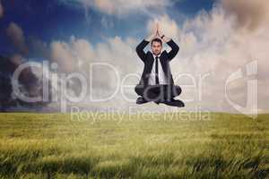 Composite image of businessman sitting in lotus pose with hands