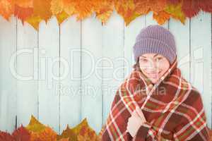 Composite image of smiling brunette with checked blanket