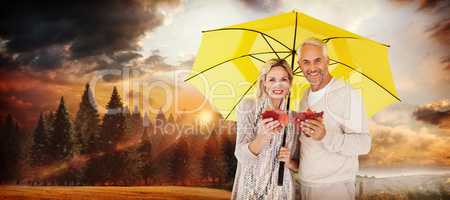 Composite image of portrait of happy couple under yellow umbrell