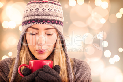 Composite image of happy blonde in winter clothes holding mug