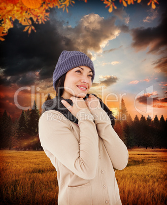 Composite image of attractive brunette looking up wearing warm c