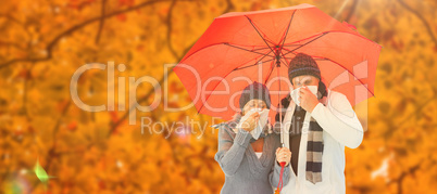 Composite image of mature couple blowing their noses under umbre