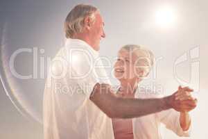 Composite image of senior couple dancing on the beach