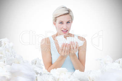 Composite image of sick woman holding tissues looking at camera