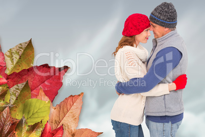 Composite image of happy couple in warm clothing hugging