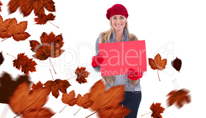 Composite image of blonde in winter clothes holding red sign