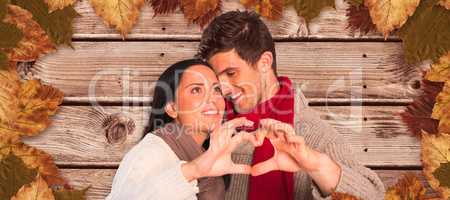 Composite image of young couple making heart with hands
