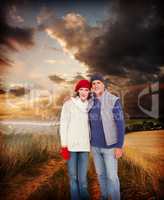 Composite image of happy couple in warm clothing