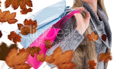 Composite image of blonde in winter clothes holding shopping bag