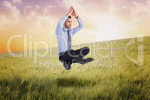 Composite image of calm businessman sitting in lotus pose with h
