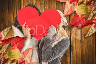 Composite image of couple behind red heart