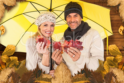 Composite image of portrait of couple holding autumn leaves whil
