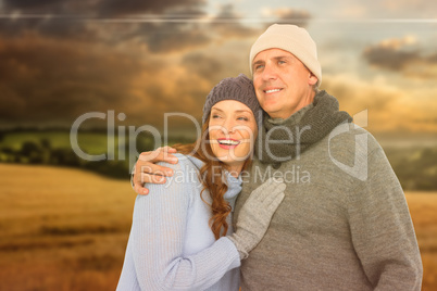 Composite image of couple in warm clothing embracing