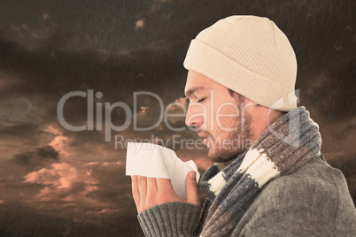 Composite image of handsome man in winter fashion blowing his no