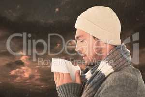 Composite image of handsome man in winter fashion blowing his no