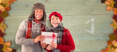 Composite image of couple smiling and holding gift
