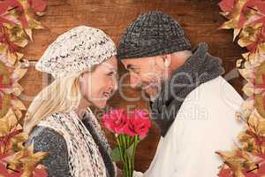 Composite image of cute couple holding rose while looking at eac