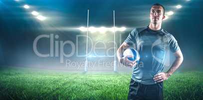 Composite image of rugby player holding ball with hand on hip