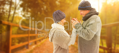 Composite image of happy mature couple in winter clothes embraci