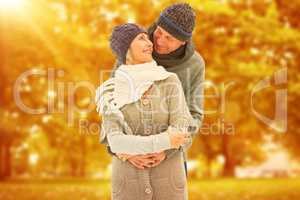 Composite image of happy mature couple in winter clothes embraci