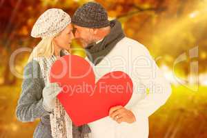 Composite image of couple holding heart while looking at each ot