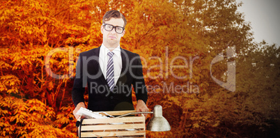 Composite image of sad geeky businessman holding box of his thin