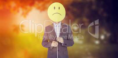 Composite image of businessman holding sad smiley in front of fa
