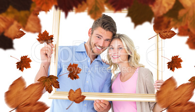 Composite image of attractive young couple holding picture frame