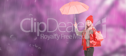 Composite image of festive blonde holding umbrella and bags