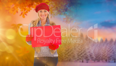 Composite image of blonde in winter clothes holding red sign