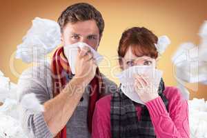 Composite image of couple blowing noses into tissues