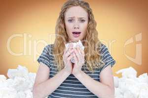 Composite image of sick woman sneezing in a tissue