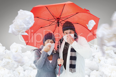 Composite image of mature couple blowing their noses under umbre