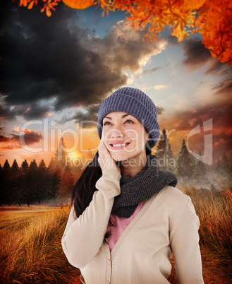 Composite image of attractive brunette looking up wearing warm c