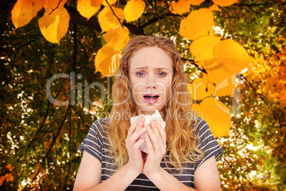 Composite image of sick woman sneezing in a tissue