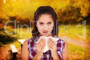 Composite image of portrait of sick woman sneezing in a tissue