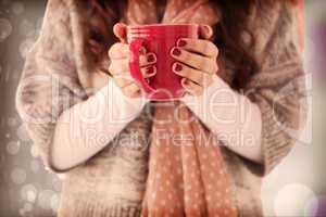 Composite image of woman in winter clothes holding a hot drink
