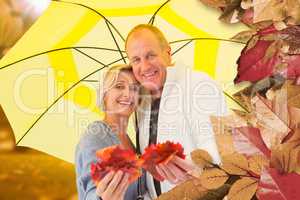 Composite image of happy mature couple showing autumn leaves und