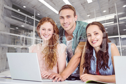 Composite image of fashion students using laptop