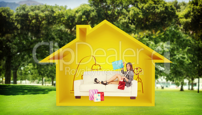 Composite image of woman lying on couch with shopping bags