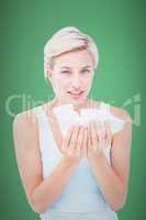 Composite image of sick woman holding tissues looking at camera