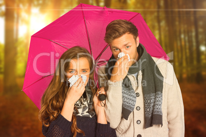 Composite image of couple blowing nose while holding umbrella