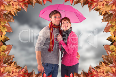 Composite image of couple standing underneath an umbrella