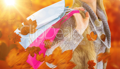 Composite image of blonde in winter clothes holding shopping bag