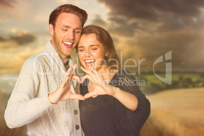 Composite image of happy couple forming heart with hands