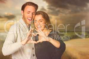Composite image of happy couple forming heart with hands