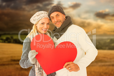 Composite image of portrait of happy couple holding heart